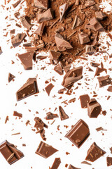 Fototapeta premium Shattered dark chocolate pieces scattered on a white surface, showcasing rich texture and delicious indulgence.