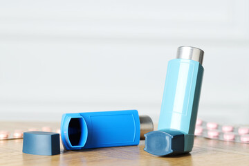 Inhalers on wooden table indoors, closeup with space for text. Asthma treatment
