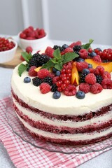 Tasty sponge cake with different fruits and mint on light grey table