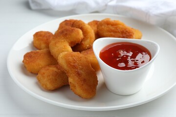 Tasty chicken nuggets with chili sauce on white table, closeup