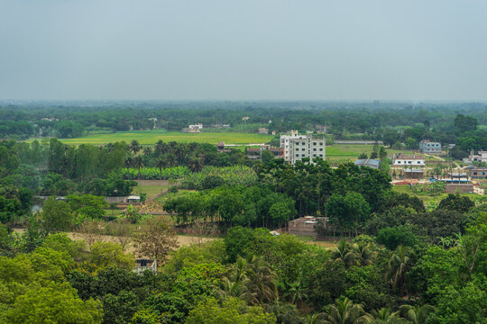 airview Landscape with green fields, scattered buildings, and dense foliage under hazy sky. Bangladesh, Rajshahi.