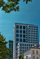 apartment high-rise with a white facade under a clear blue sky and a bit of green in the foreground