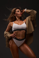 Obraz premium Young fit woman in tracksuit, black background. muscle relief. pumped up buttocks, sportswoman, fitness bikini