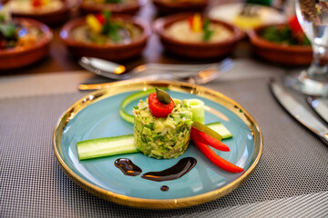 Vegetarische Speise aus Gemüse extravagant angerichtet auf einem hellblauen Teller mit goldenen Rand im Restaurant Hotel
