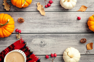 Autumn flat lay. Frame of orange and white pumpkins, fall leaves, plaid with cup of coffee on wooden desk table.