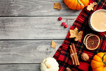 Autumn aesthetic table with plaid, dry leaves, pumpkins, coffee cup on wooden desk table. Flat lay, top view.