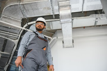 An Indian worker inspects the ventilation system in an office building
