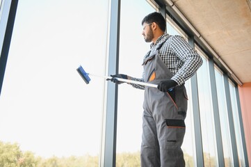 Cheerful male person cleaning window