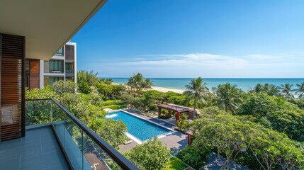 Fototapeta premium Spacious balcony view from a serviced condominium in Hua Hin, Thailand, overlooking a pool, lush trees, and a beautiful beach with clear blue skies above