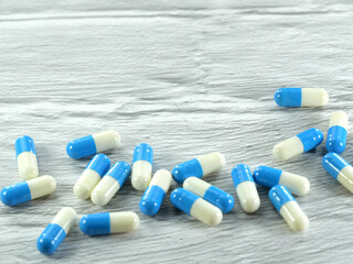 A lot of white and blue capsules on a white-gray background with copy space.