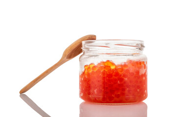 Red caviar in a glass jar with a spoon, macro, isolated on a white background