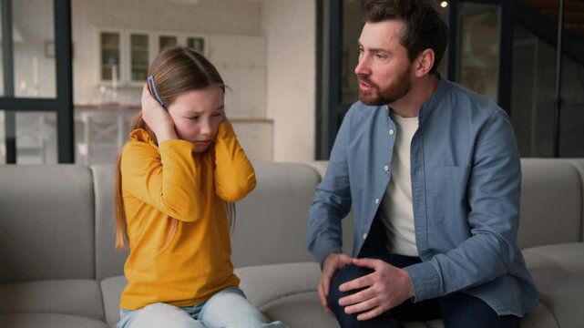 Annoyed Caucasian man dad male screaming shout on little kid disobedience scold child offended naughty daughter girl ignore avoid angry father closing ears with hands at home family conflict argument