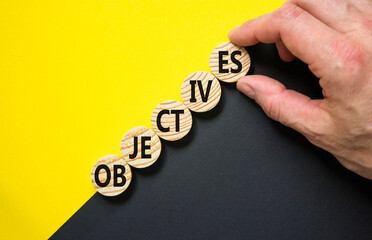 Objectives symbol. Concept word Objectives on beautiful wooden circles. Beautiful yellow and black background. Businessman hand. Business objectives concept. Copy space.