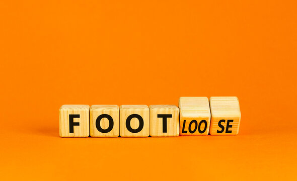 Naklejki Foot or footloose symbol. Businessman turns wooden cubes and changes word Foot bad to Footloose. Beautiful orange table orange background. Business foot or footloose concept. Copy space.