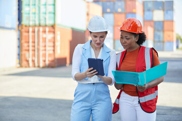 worker or engineer talking about work and project with businesswoman in containers warehouse storage