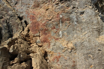 Ancient stone walls, brown and very old, with painted patterns on the surface.