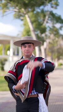 var&oacute;n joven con traje tradicional huaso chileno bailando cueca y posando en la plaza de la ciudad 
