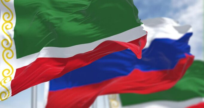Flags of Chechnya and Russia waving in the wind on a clear day