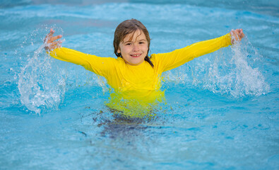 Kid splashing water in pool. Little kid splashing in blue water of swimming pool. Cute child swimming and splashing water with drops in pool. Child splashing and having fun in swim poolside.