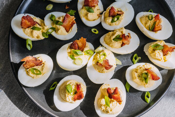 Deviled eggs garnished with bacon and green onion