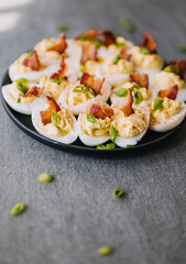 Deviled eggs garnished with bacon, green onion and smoked paprika
