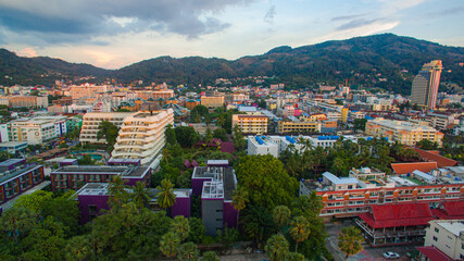 Fototapeta premium A breathtaking aerial view of a coastal bay at sunset, with golden light reflecting on the calm sea and silhouetted hills in the distance. beautiful reflection of the golden sun at Patong Bay Phuket.
