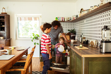 Children helping father with the dishes in the kitchen