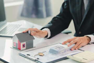 Businessman, house and condo sales agent, handing over keys to clients and signing sales or rental agreements at the office. Real estate business concept.