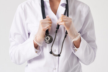 Cropped view of young female doctor holding stethoscope hanging on her neck, studio shot over white background