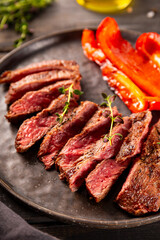 Grilled beef steak, well done with seasons on a black wooden background and plate close up vertical photo
