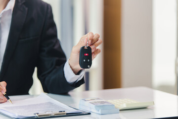 Fototapeta premium Car salesman signs car sales contract with cash and hands over keys to customer. Automotive business concept.