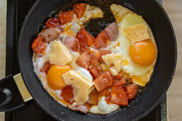 Fried eggs with tomatoes and cheese in frying pan. Soft focus. Frittata