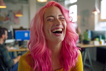 A joyful woman with pink hair laughs in a vibrant office, enjoying the energetic atmosphere.