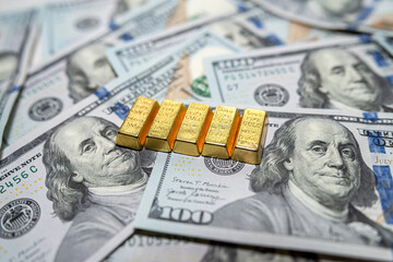 group of gold bar lie on 100 US dollar bills background