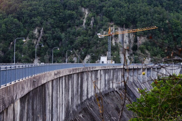 Construction crane working on a dam in a mountain forest