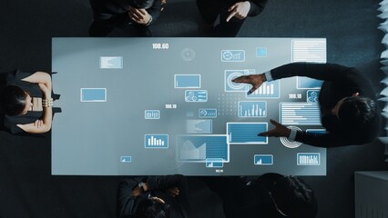 Top down aerial of collaborate professional diverse business people discuss marketing strategy with hologram of marketing data analysis graph, diagram or financial profit investment plan. Directorate.