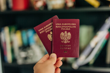 man hand holds a Polish passports, symbolizing migration and citizenship