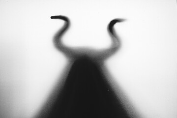 Horror, halloween background - Shadowy figure with horns behind the glass