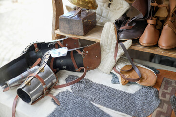 Display of medieval armor and accessories, including chainmail, gauntlets, and leather boots, on a wooden table, showcasing historical craftsmanship and reenactment props