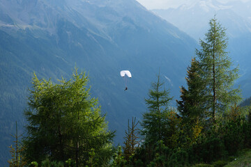 A lone paraglider hangs in the air in front of the alps, austria, tirol