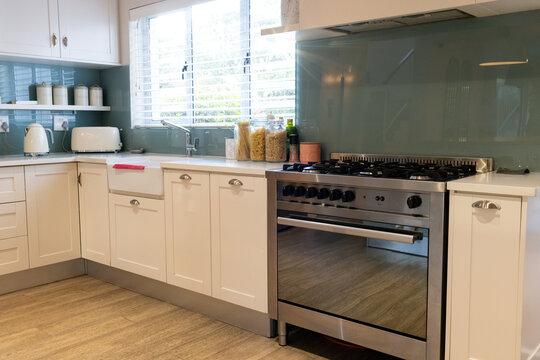 Modern kitchen with stainless steel stove, white cabinets, and countertop appliances, copy space