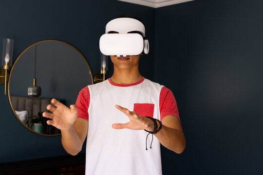 Using VR headset, asian man interacting with virtual environment in modern home