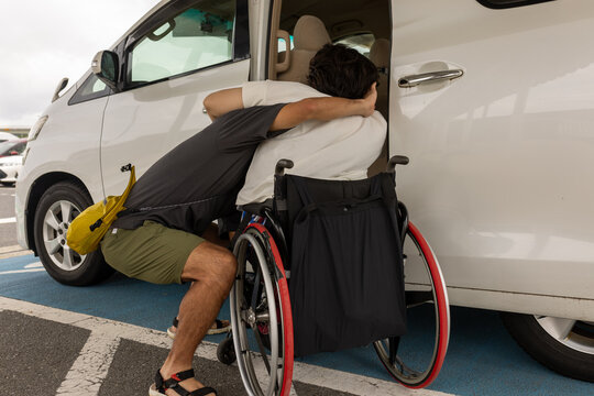 日本人の車椅子に乗った女性を男性が車に乗ろうとしている