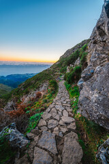 Fototapeta premium Hiking on the highest peak of Madeira Pico Ruivo next to the cottage Abrigo do Pico Ruivo. Views of the surrounding mountains lanscape during sunrise