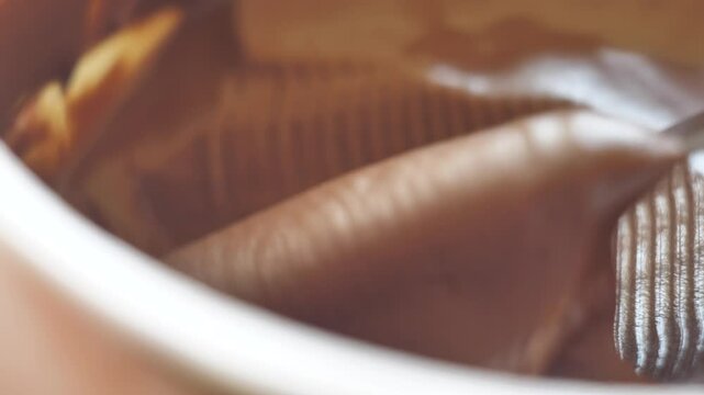 Mega close-up table knife took chocolate butter from a jar. Sandwich with white bread and hazelnut paste. Nutritious breakfast with cocoa paste and bread