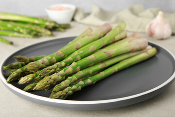 Fresh green asparagus stems on gray table, closeup