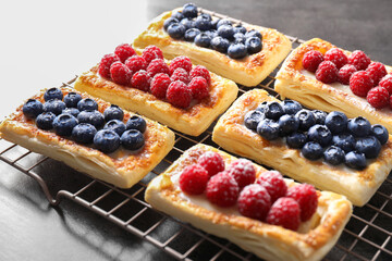Tasty puff pastries with berries on grey table, closeup