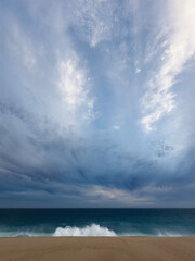 Wave if crashing over sandy beach on a moody stormy day