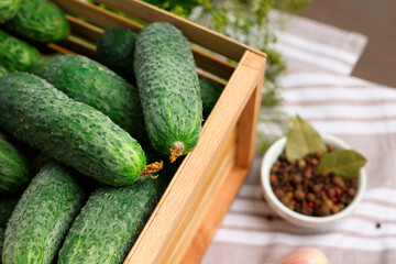 Fresh green cucumbers in wooden crate on table, closeup