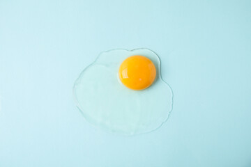 One raw egg on light blue background, top view